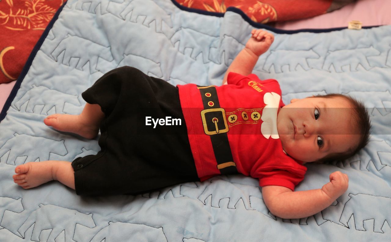 HIGH ANGLE VIEW OF BABY BOY LYING ON BED AT HOME