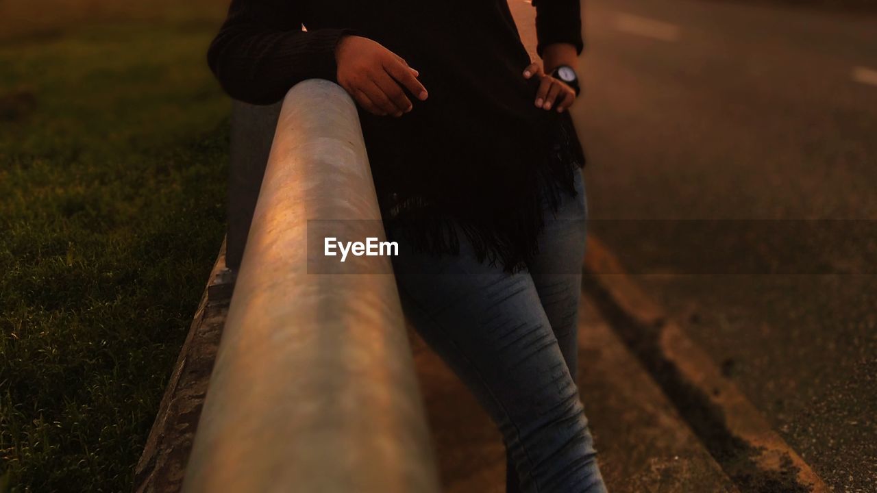 Midsection of woman leaning on railing at night