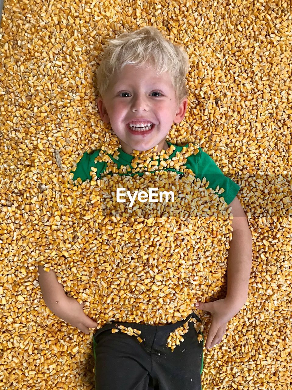 High angle portrait of cute boy lying on corns