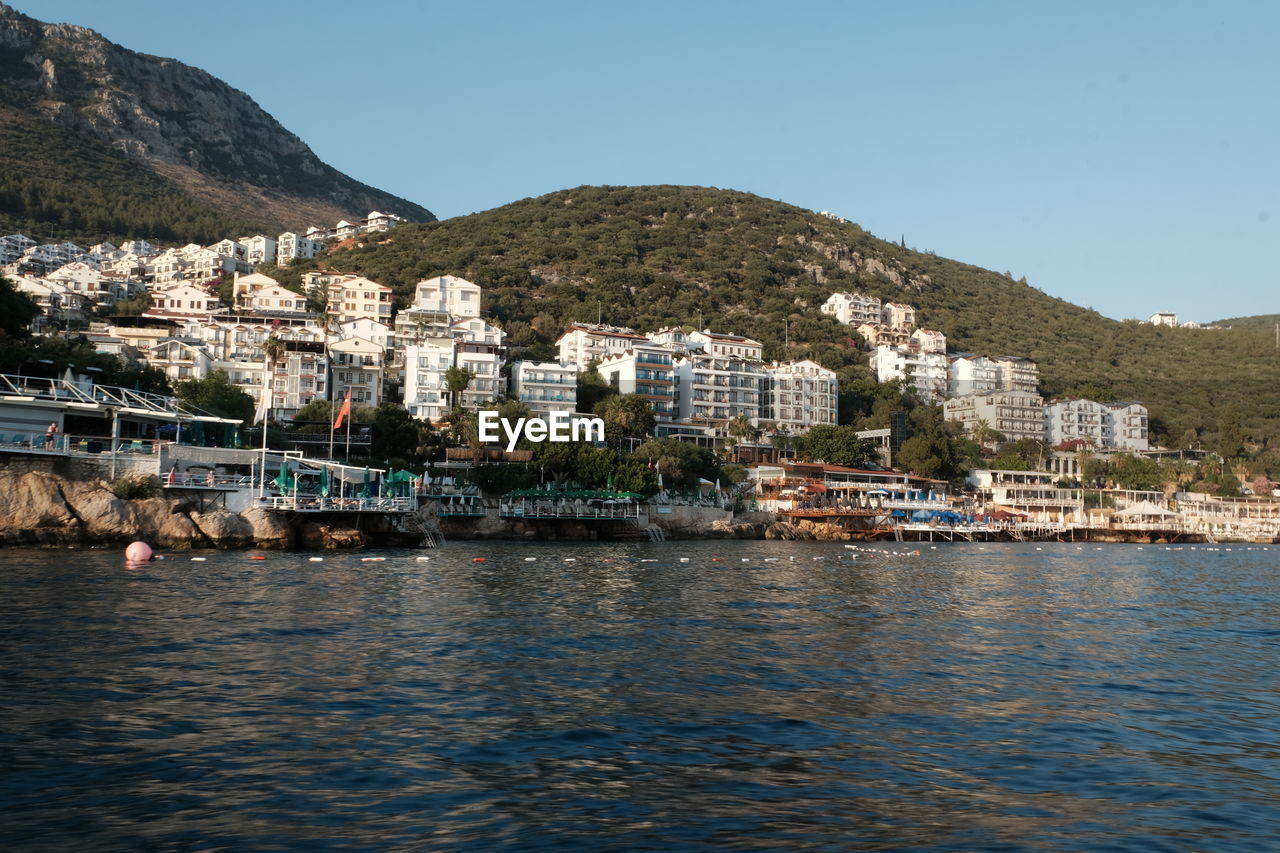 water, architecture, building exterior, building, built structure, city, sea, mountain, sky, nature, land, coast, clear sky, travel destinations, waterfront, town, residential district, house, transportation, bay, beach, no people, harbor, travel, tourism, coastline, nautical vessel, landscape, cityscape, vehicle, environment, vacation, day, village, outdoors, sunny, community, body of water, scenics - nature, mode of transportation, ship, blue, beauty in nature, holiday, trip, tree, mountain range, tranquility