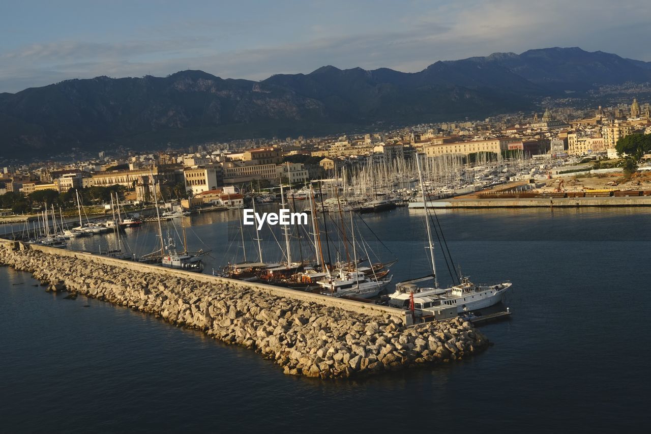 water, transportation, architecture, nautical vessel, sea, coast, harbor, nature, mode of transportation, built structure, mountain, sky, vehicle, dock, building exterior, bay, reflection, city, ship, no people, marina, building, travel, travel destinations, port, outdoors, sailboat, boat, day, dusk, aerial photography, waterfront, high angle view, cityscape, evening, pier, land, moored, mountain range, watercraft, cloud