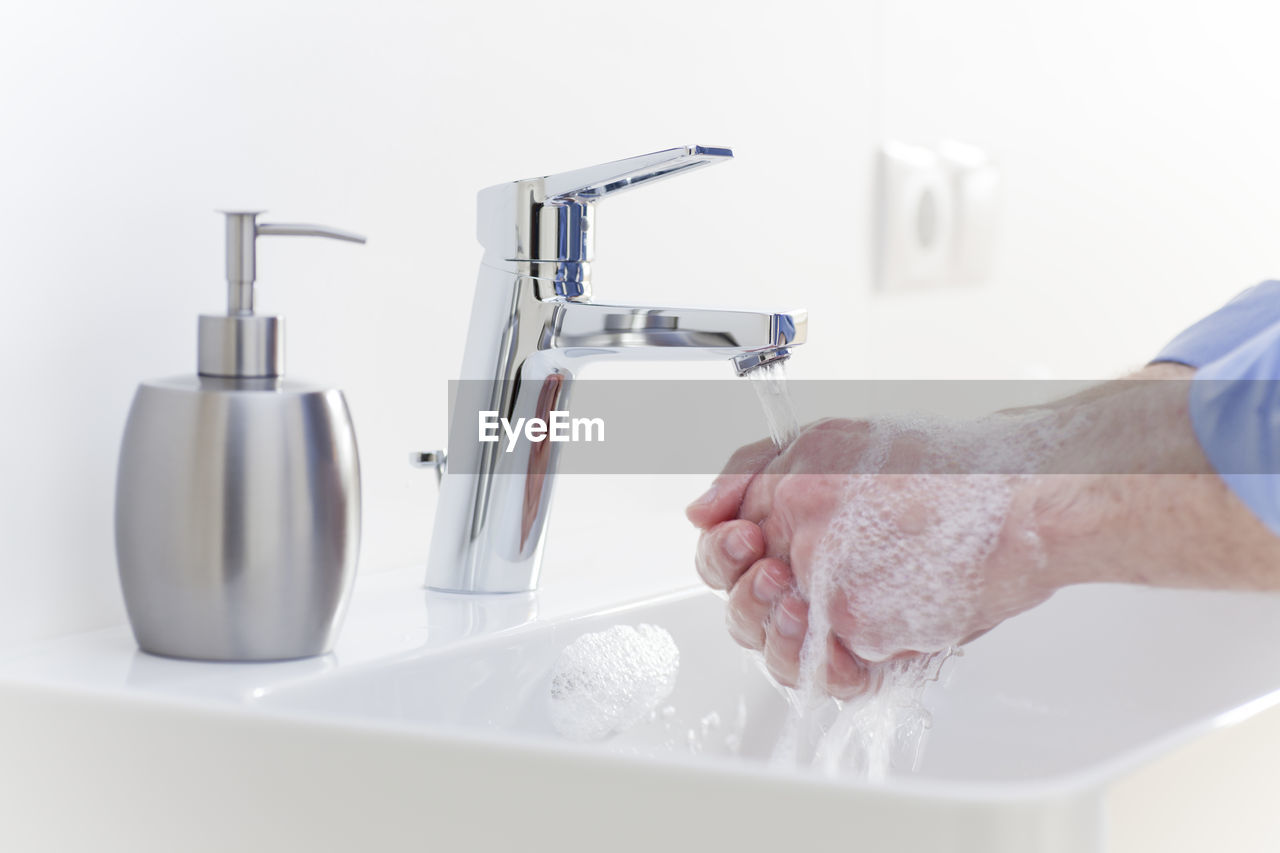 Close-up of person washing hands in sink