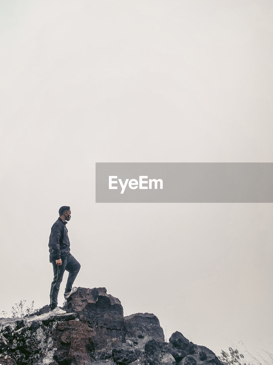 Man standing on rock against sky