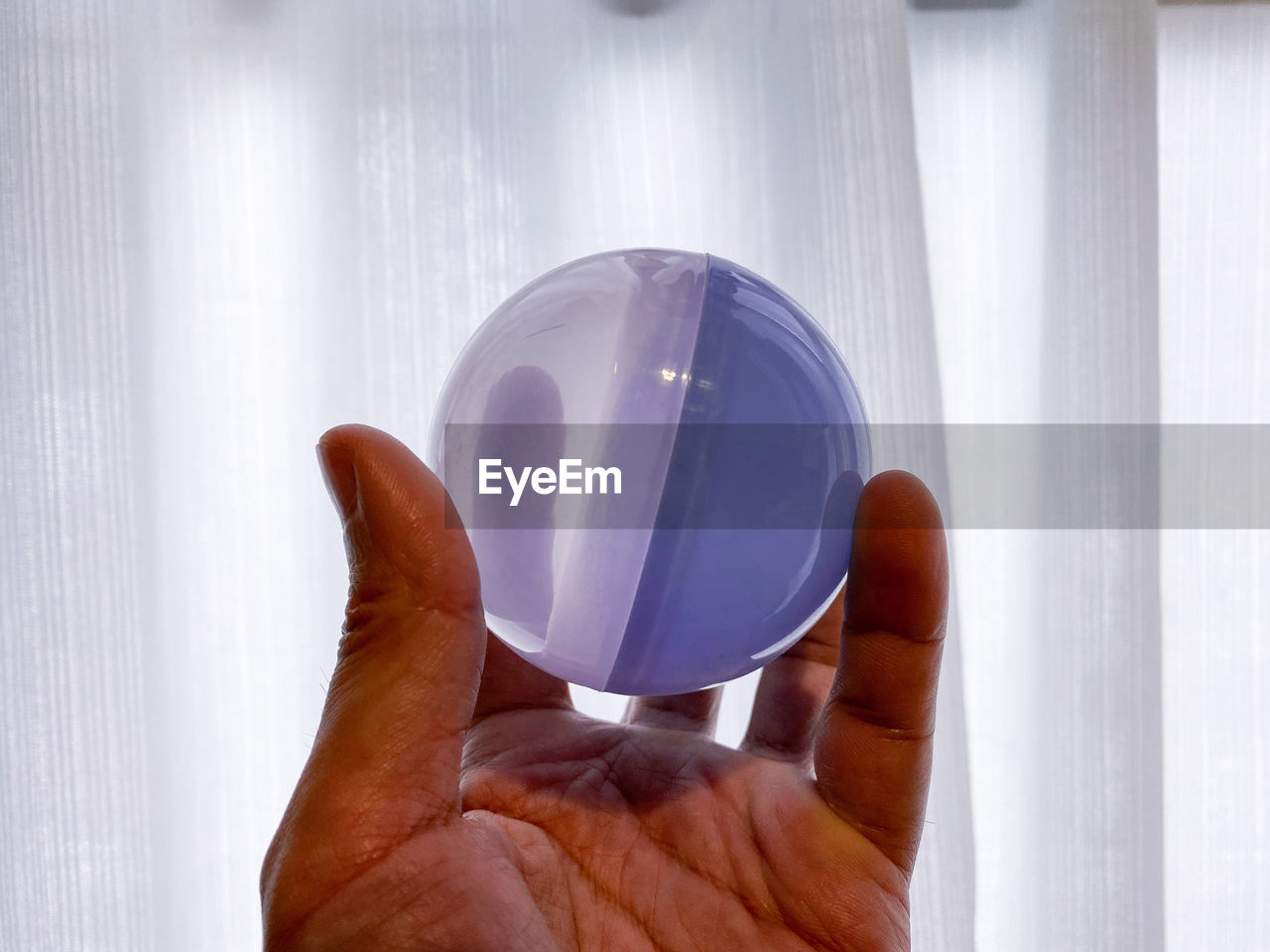 CLOSE-UP OF HAND HOLDING CRYSTAL BALL