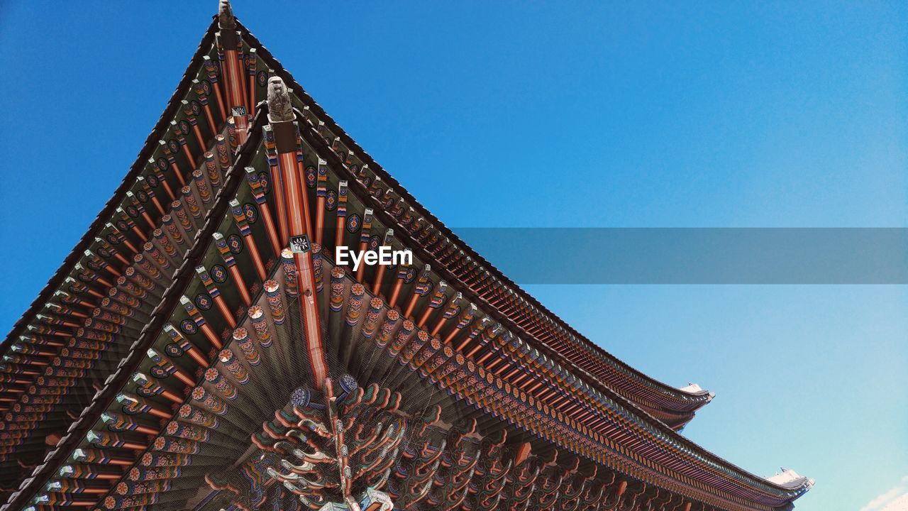 Low angle view of gyeongbokgung palace roof against clear blue sky