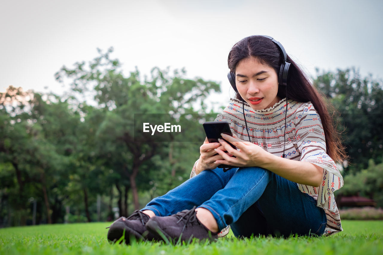 Woman listening music while sitting at park