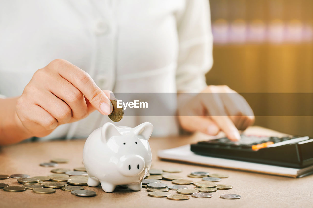 Woman hand holding coins putting in piggy bank. concept saving money for finance accounting