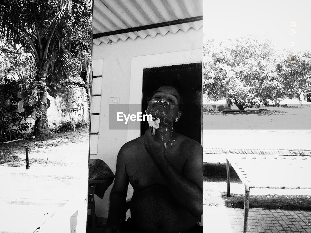 Portrait of shirtless man standing against mirror