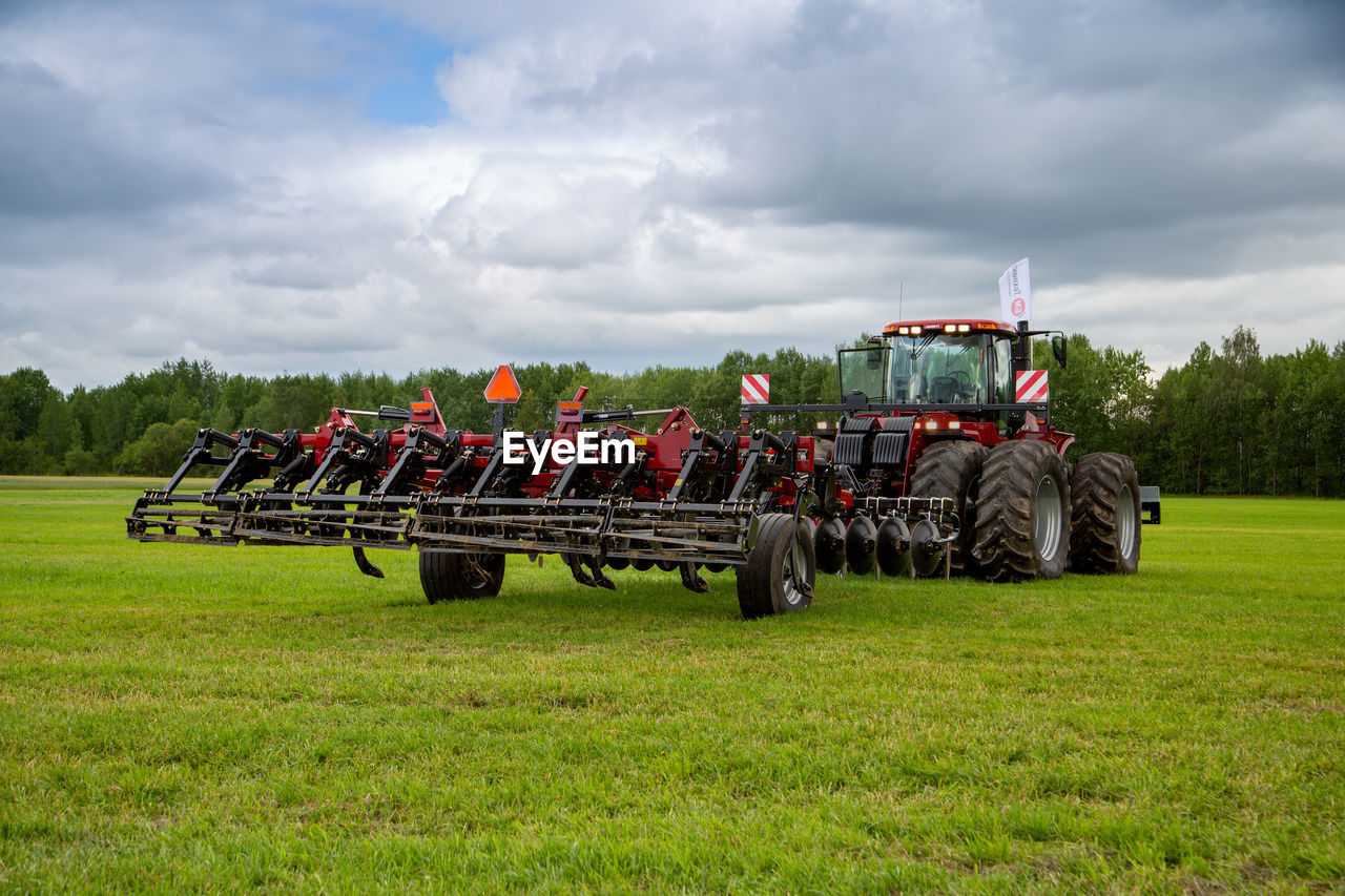 field, tractor, agriculture, plant, sky, transportation, grass, nature, agricultural machinery, cloud, farm, landscape, land, agricultural equipment, vehicle, rural scene, mode of transportation, green, environment, land vehicle, day, rural area, occupation, machinery, outdoors, plough, no people, crop, harvester