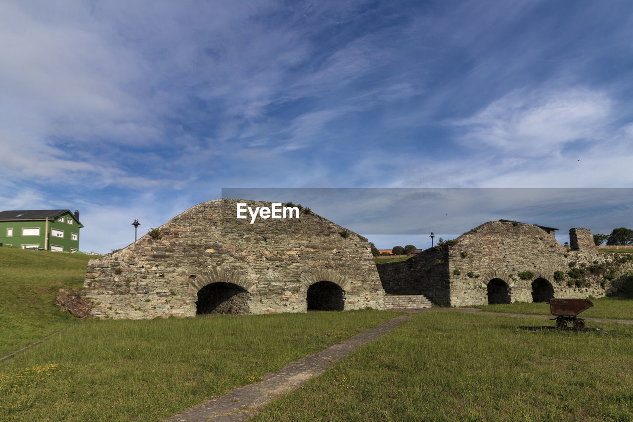 architecture, history, built structure, the past, sky, grass, ruins, building, cloud, rural area, ancient, nature, fortification, building exterior, travel destinations, plant, landscape, travel, no people, land, old ruin, old, tourism, stone material, cemetery, arch, outdoors, religion, field, abbey, environment, grave, ancient history, rural scene, medieval