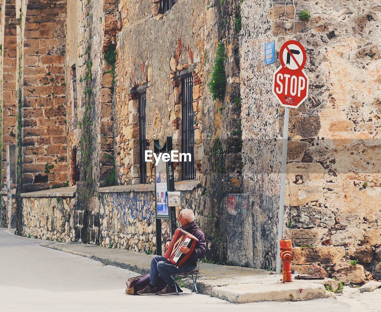 MAN SITTING ON WALL BY ROAD