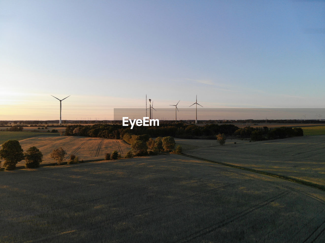 WIND TURBINES ON FIELD AGAINST CLEAR SKY