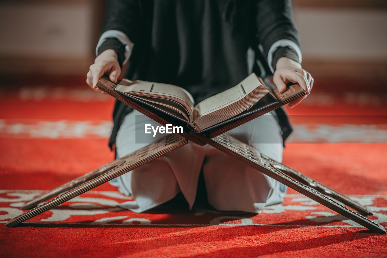 Midsection of woman with koran at mosque