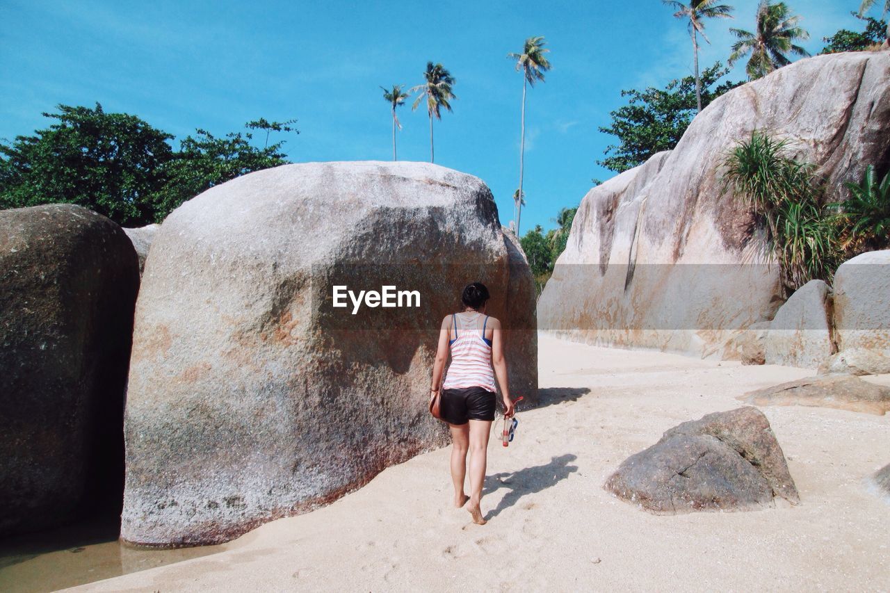 FULL LENGTH REAR VIEW OF WOMAN WALKING ON ROCK