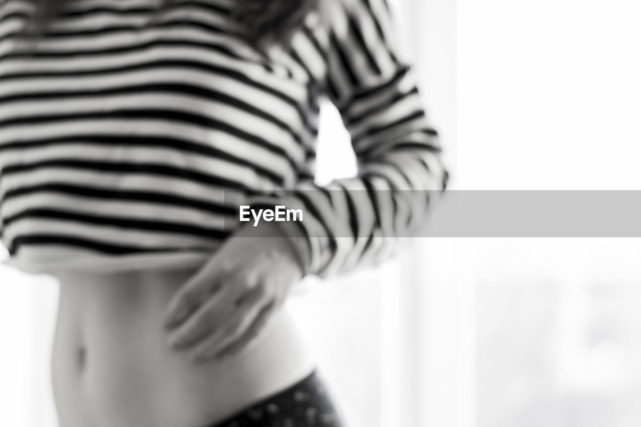 Midsection of young woman wearing striped crop top at home