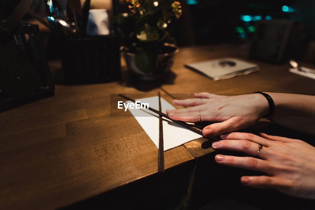 Close-up of woman holding chopsticks and paper on table