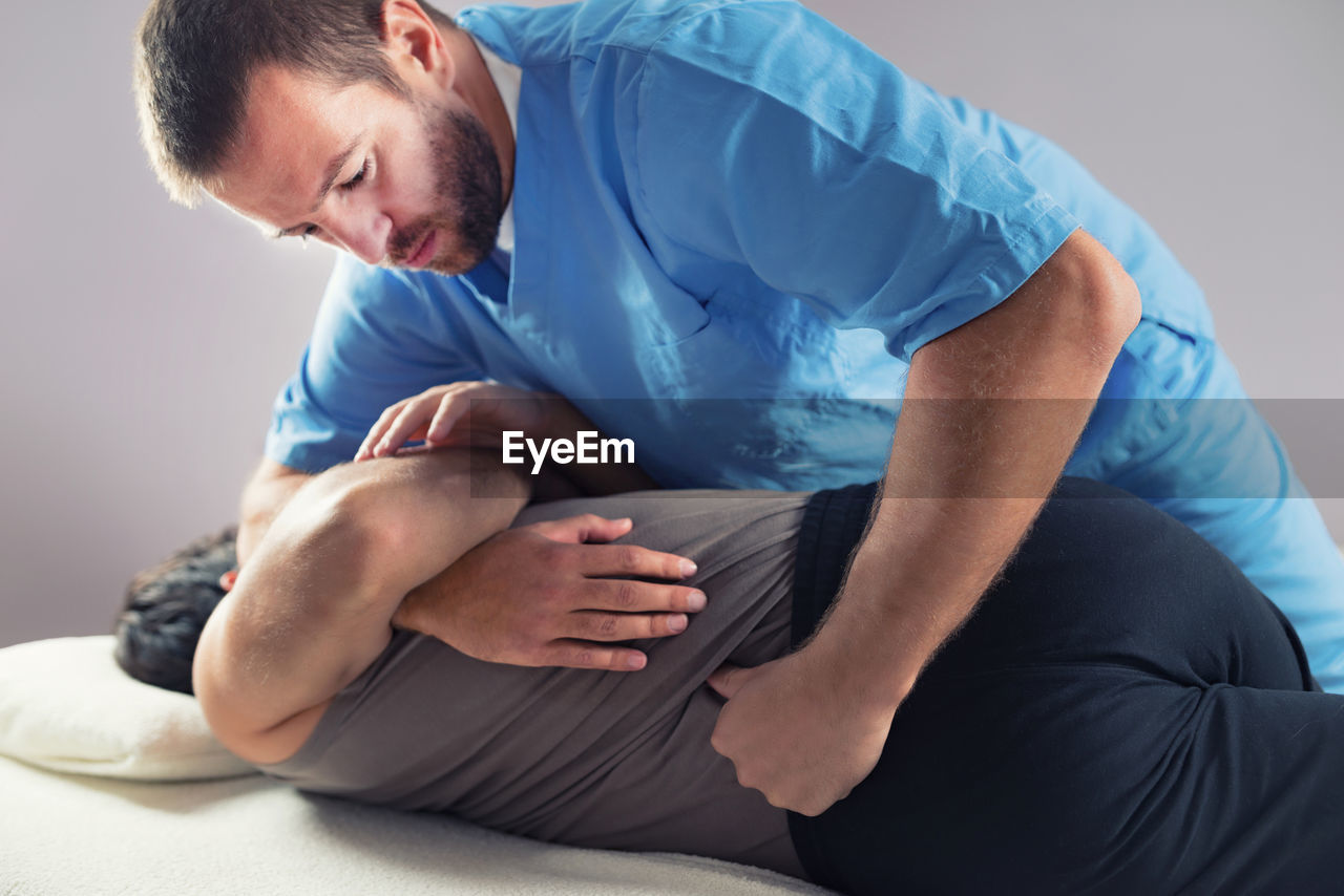 Man receiving massage therapy while lying on bed