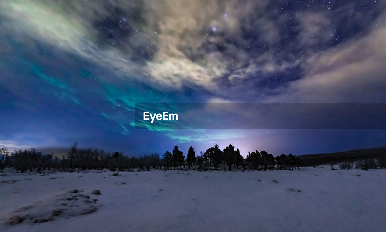 Scenic view of snowy field against sky at night