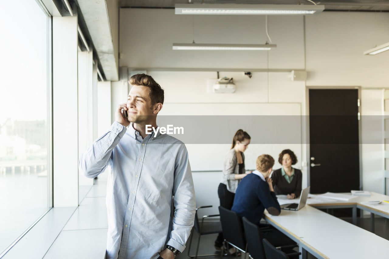 Young man talking on smart phone in classroom