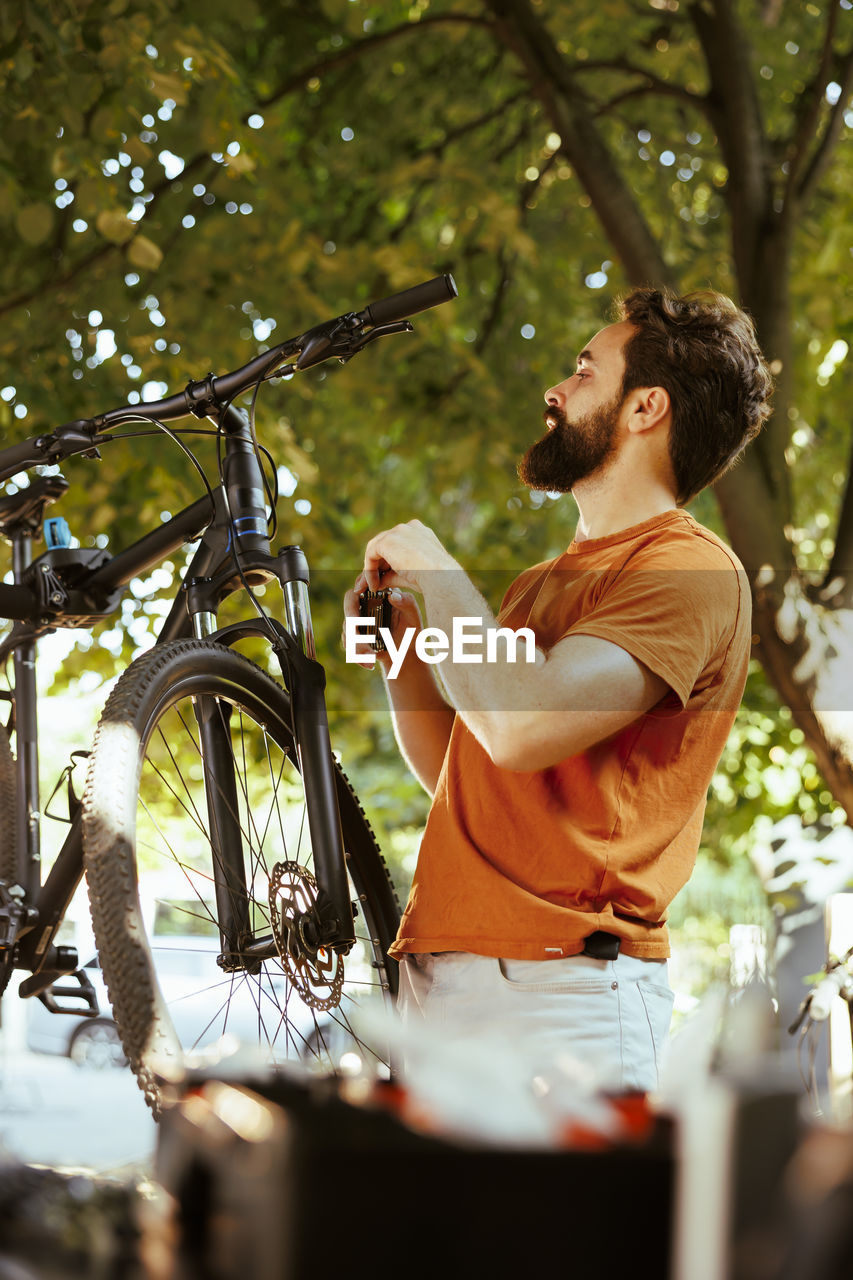 side view of young woman with bicycle against trees