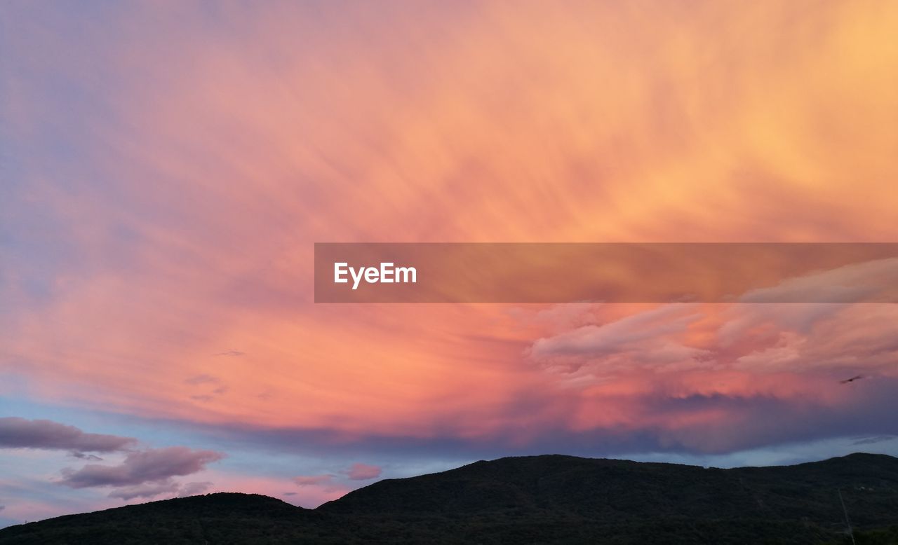 Low angle view of silhouette mountain against cloudy sky