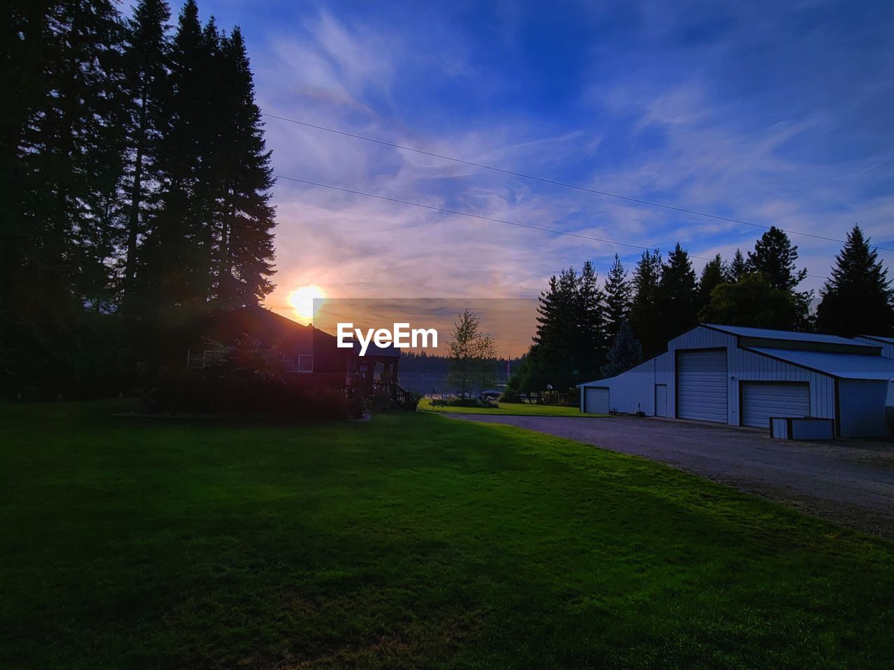 HOUSES ON FIELD AGAINST SKY DURING SUNSET