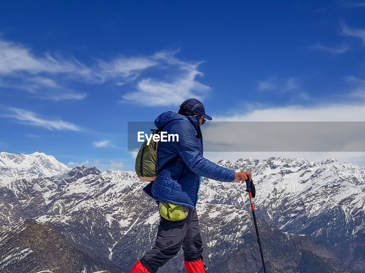 Hiker walking with snowcapped mountain in background against sky