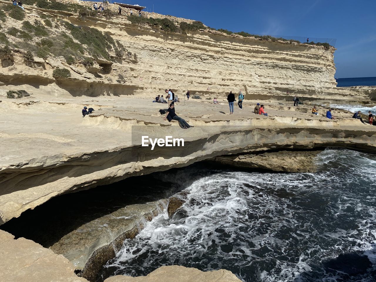 PEOPLE WALKING ON ROCKS BY LAND