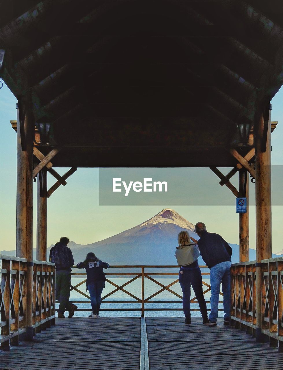 REAR VIEW OF MAN AND WOMAN STANDING ON PIER