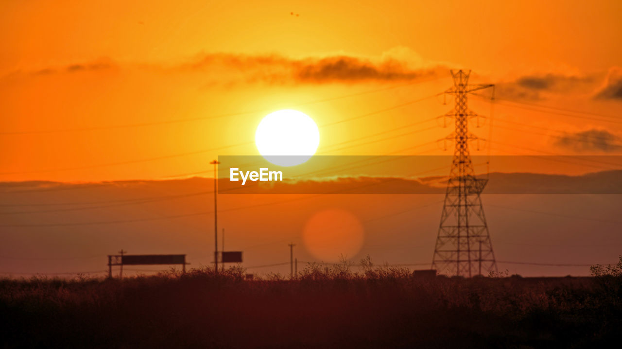 SILHOUETTE ELECTRICITY PYLONS ON FIELD AGAINST SKY DURING SUNSET