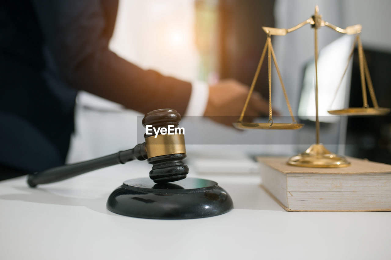 CLOSE-UP OF HAND HOLDING WINEGLASS AGAINST TABLE