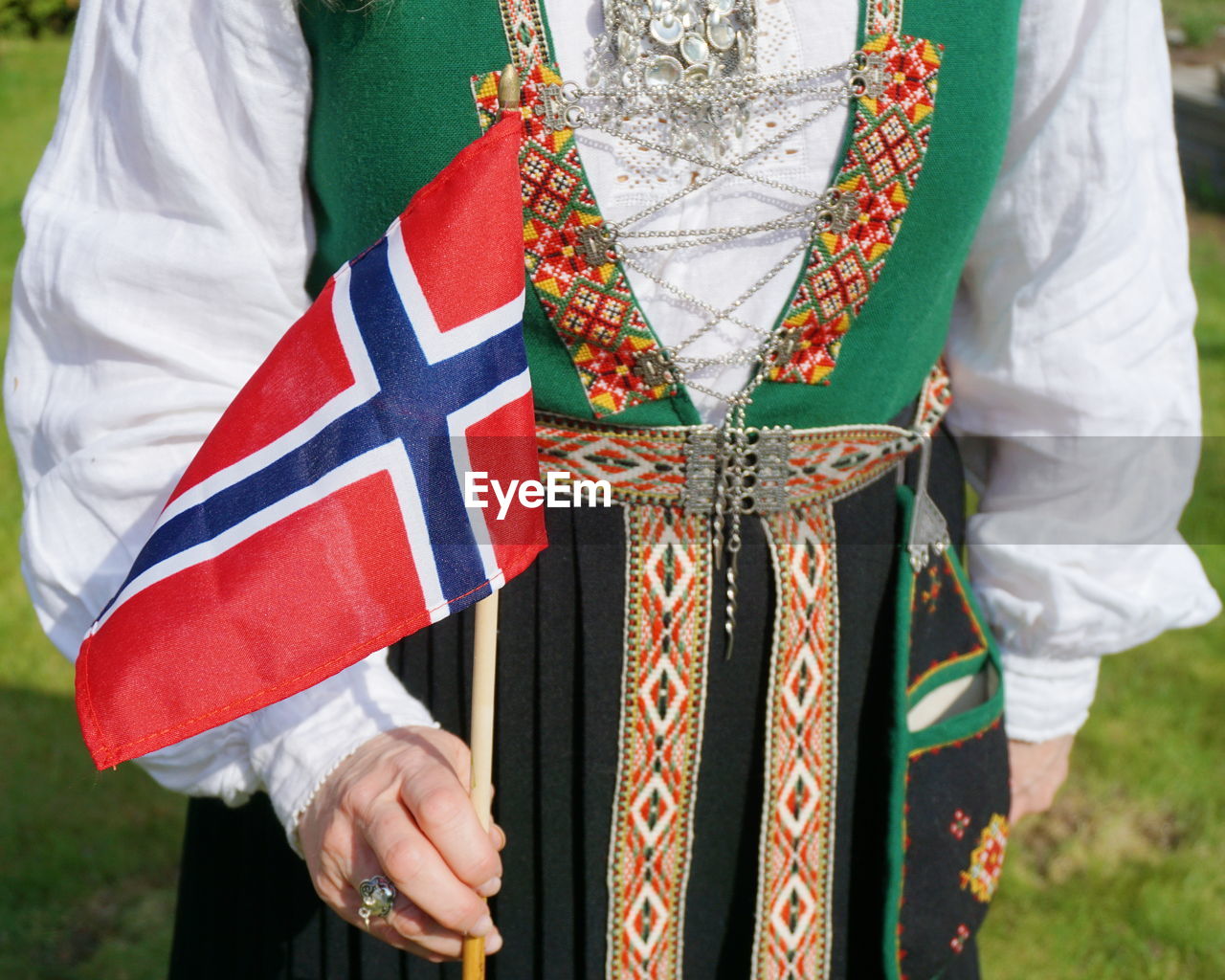 Midsection of woman wearing traditional clothing while holding norwegian flag