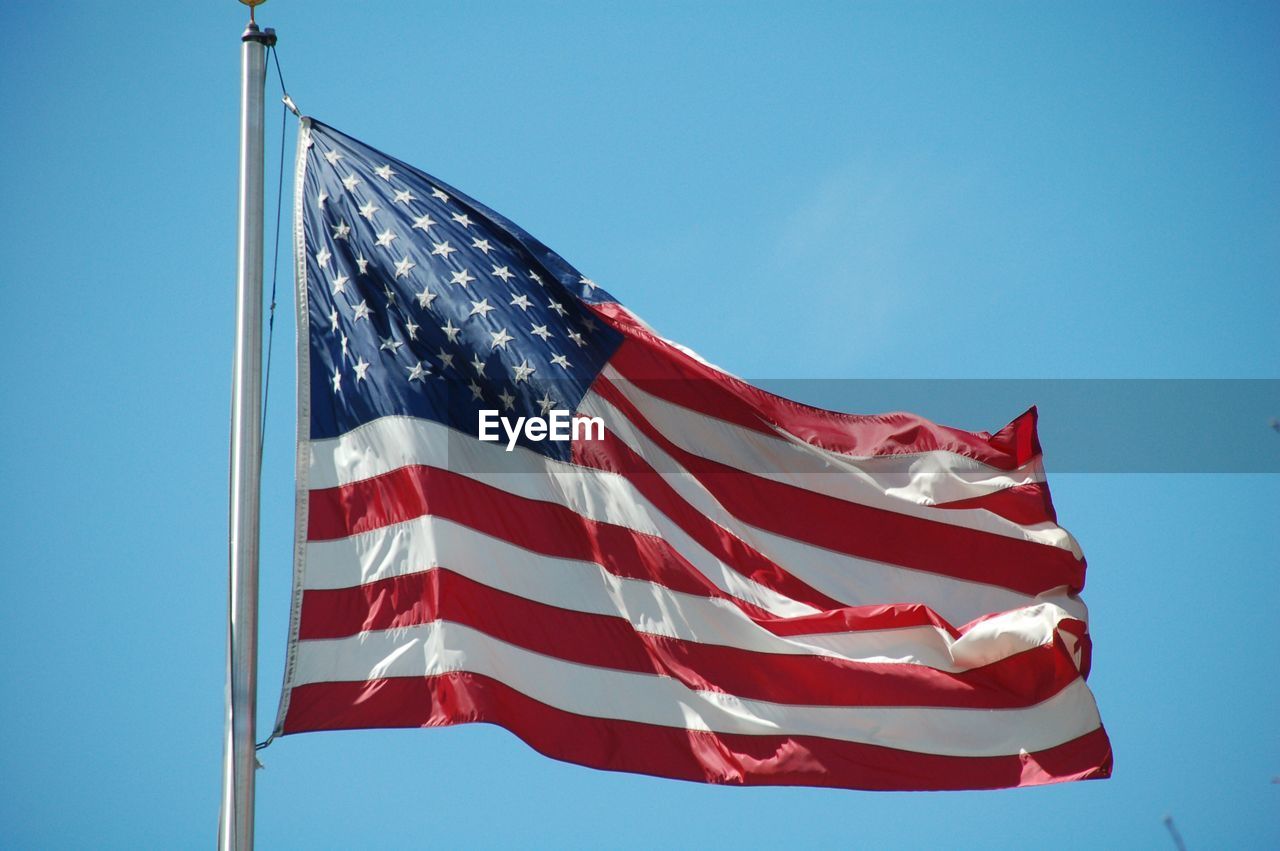 Low angle view of flag against blue sky