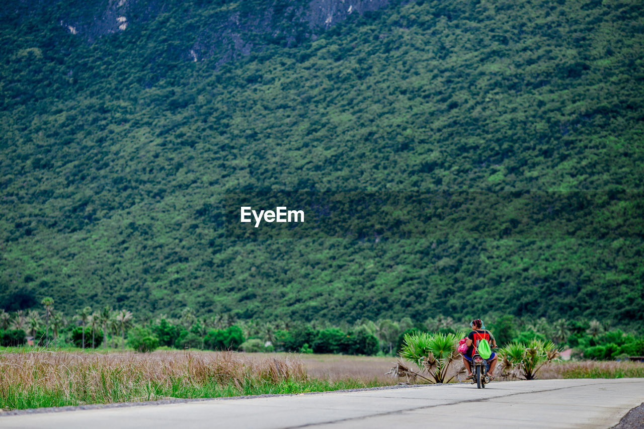 Rear view of woman on motorcycle against green mountains