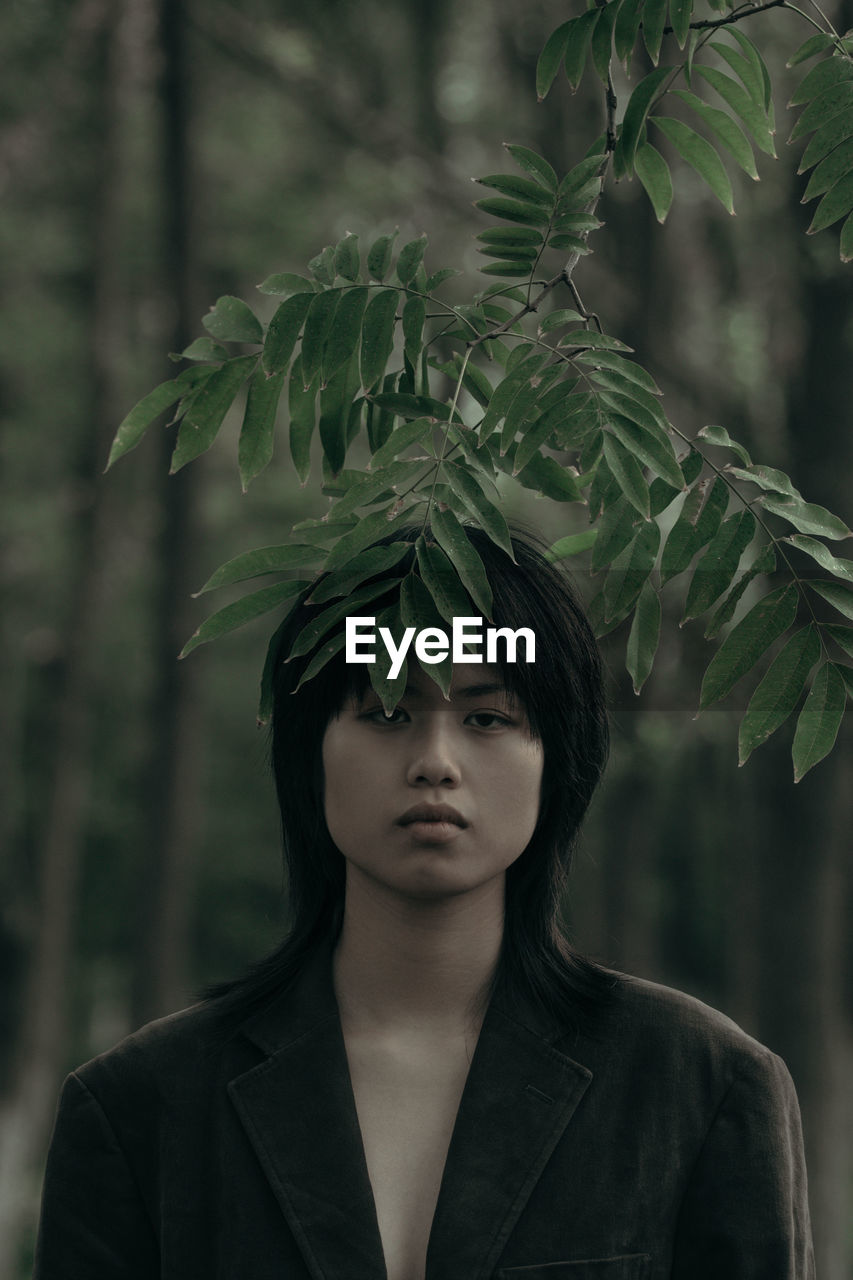 PORTRAIT OF BEAUTIFUL YOUNG WOMAN WITH LEAVES OUTDOORS