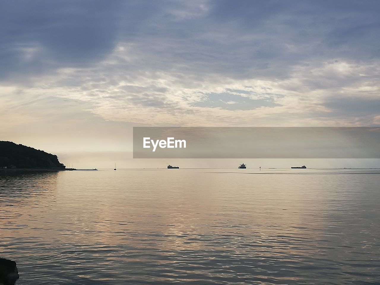 SILHOUETTE BOATS IN SEA AGAINST SKY DURING SUNSET