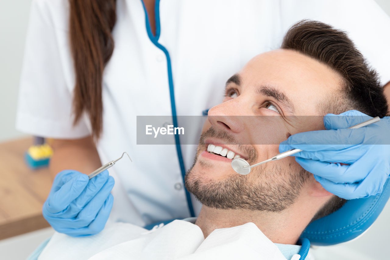 Dentist examining smiling patient at clinic