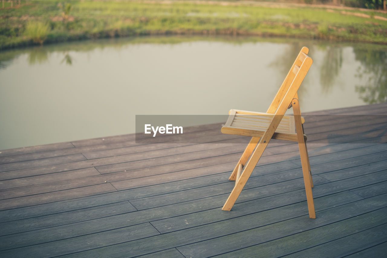 Wooden chair on balcony terrace patio for resting near pond