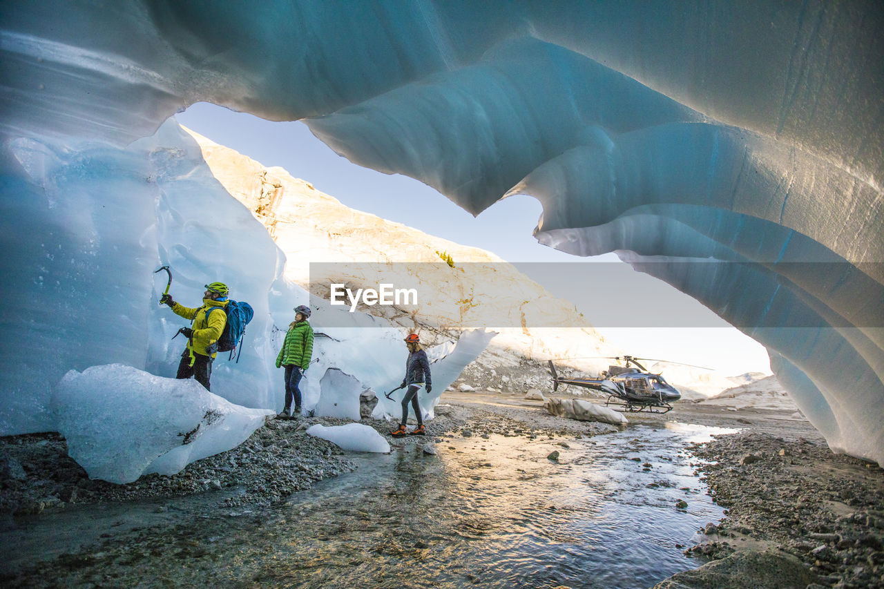 Mountain guide brings two female clients into ice cave to go climbing.