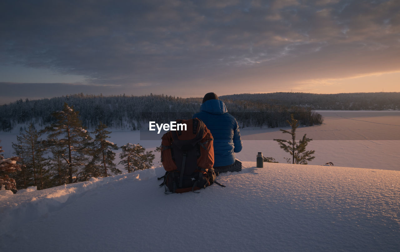 The hiker is resting on a snow-covered hillside in a stunningly beautiful place. dramatic light