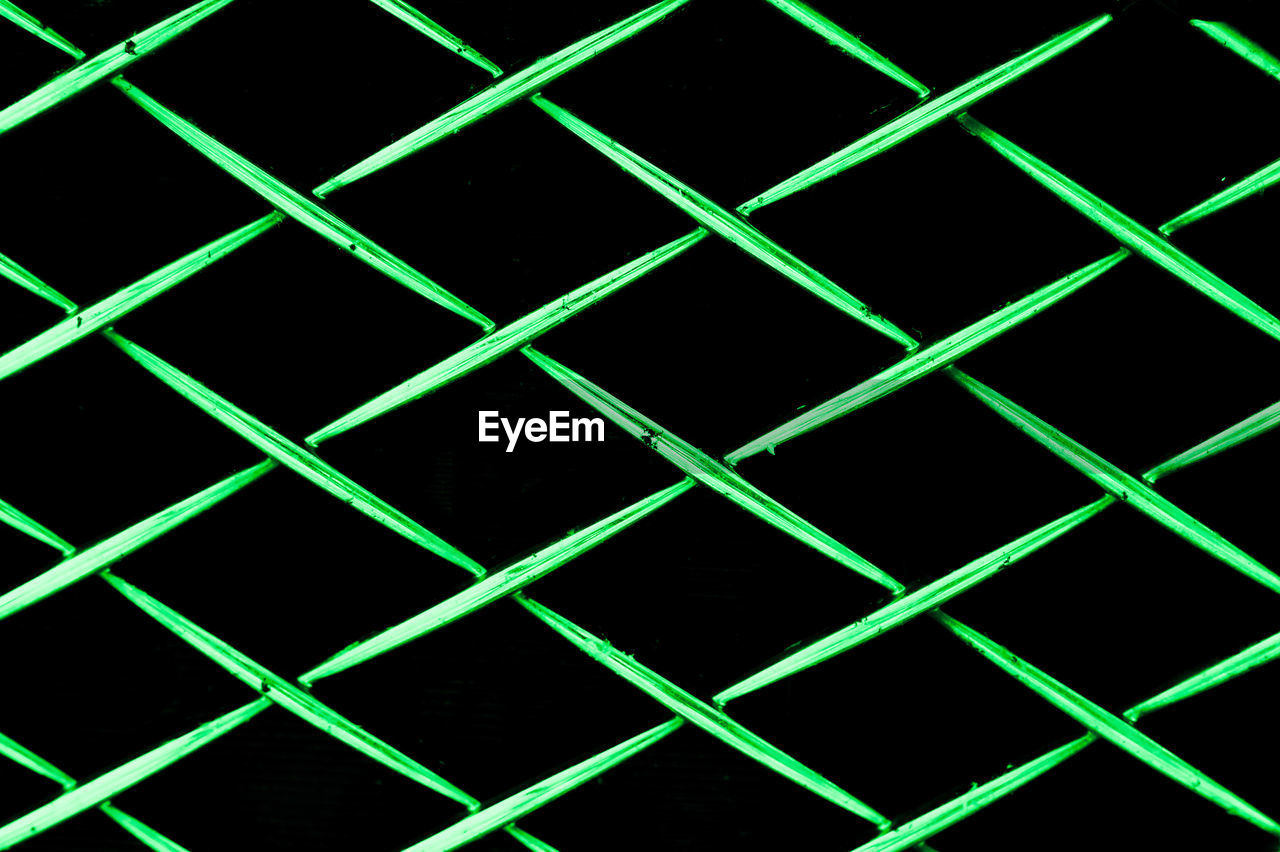 Full frame shot of green chainlink fence against black background