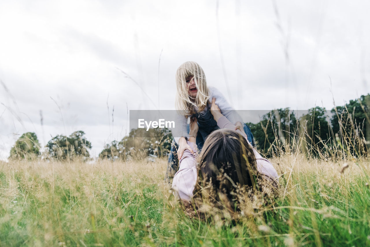 Playful mother and daughter playing on meadow