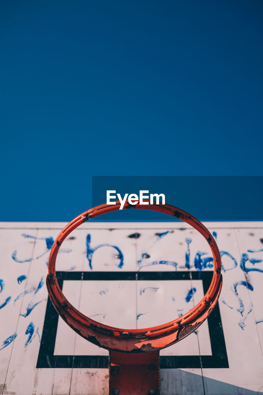 Low angle view of broken basketball hoop against clear blue sky