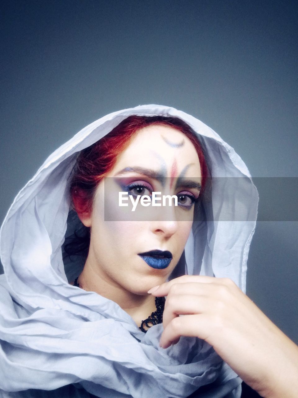 Close-up portrait of young woman with make-up over black background