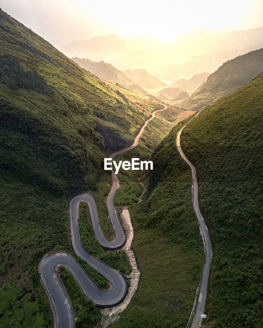 Scenic view of road among mountains against sunny sky