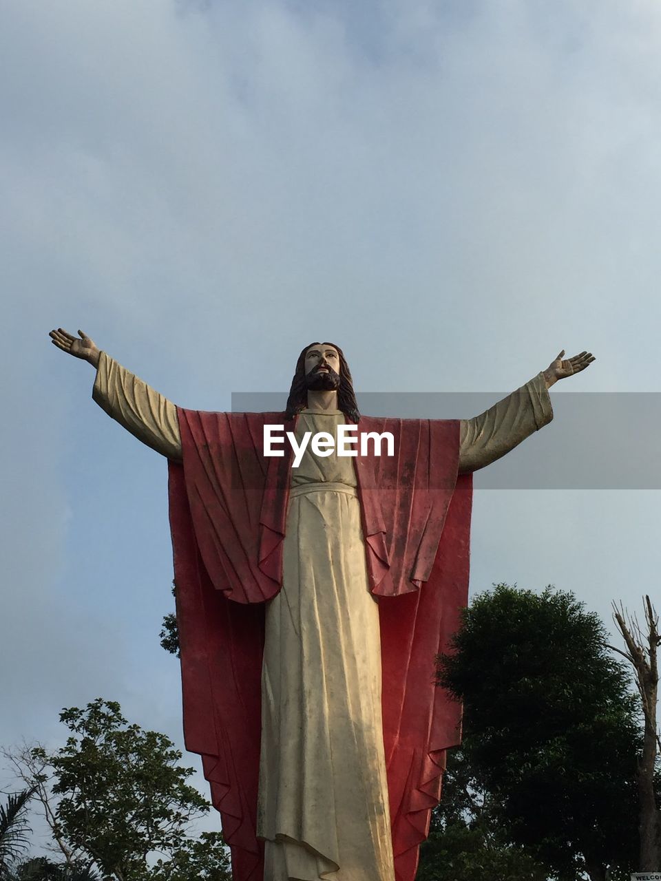 Low angle view of jesus christ statue against cloudy sky