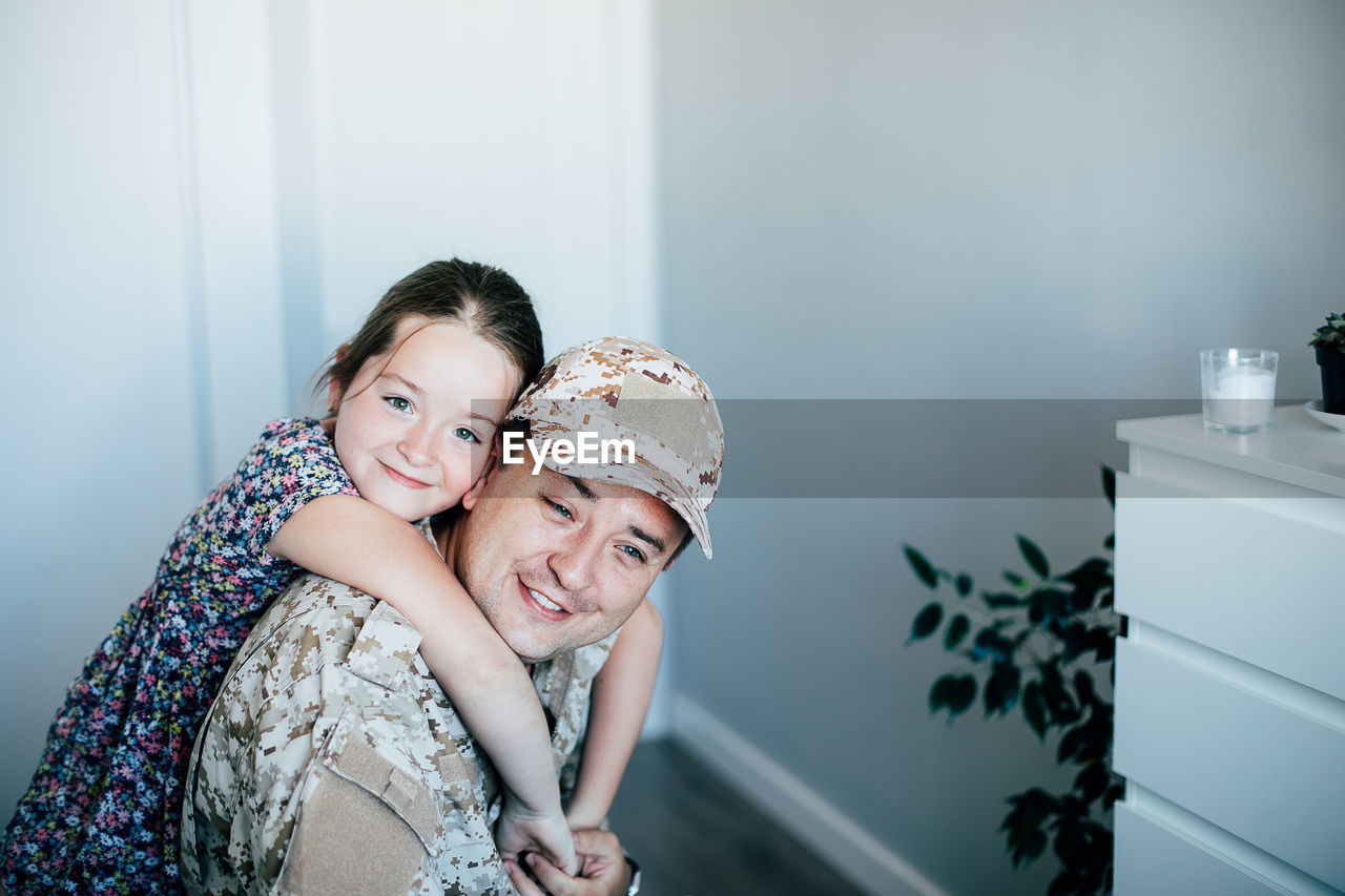 Portrait of girl embracing father in military uniform