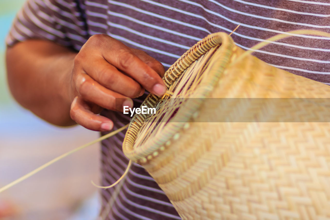 Midsection of man making wicker decoration
