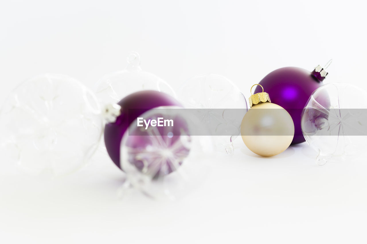 Still life with decorative transparent and purple christmas glass balls on white background