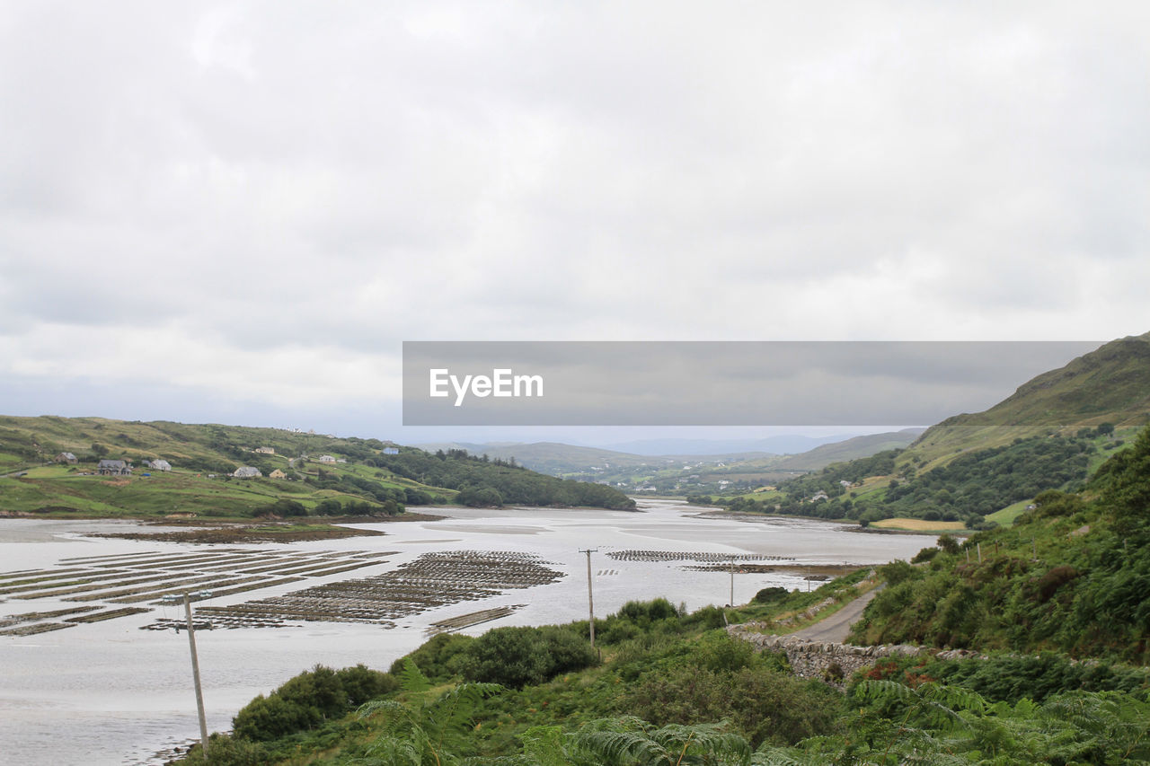 Scenic view of river and mountains against cloudy sky